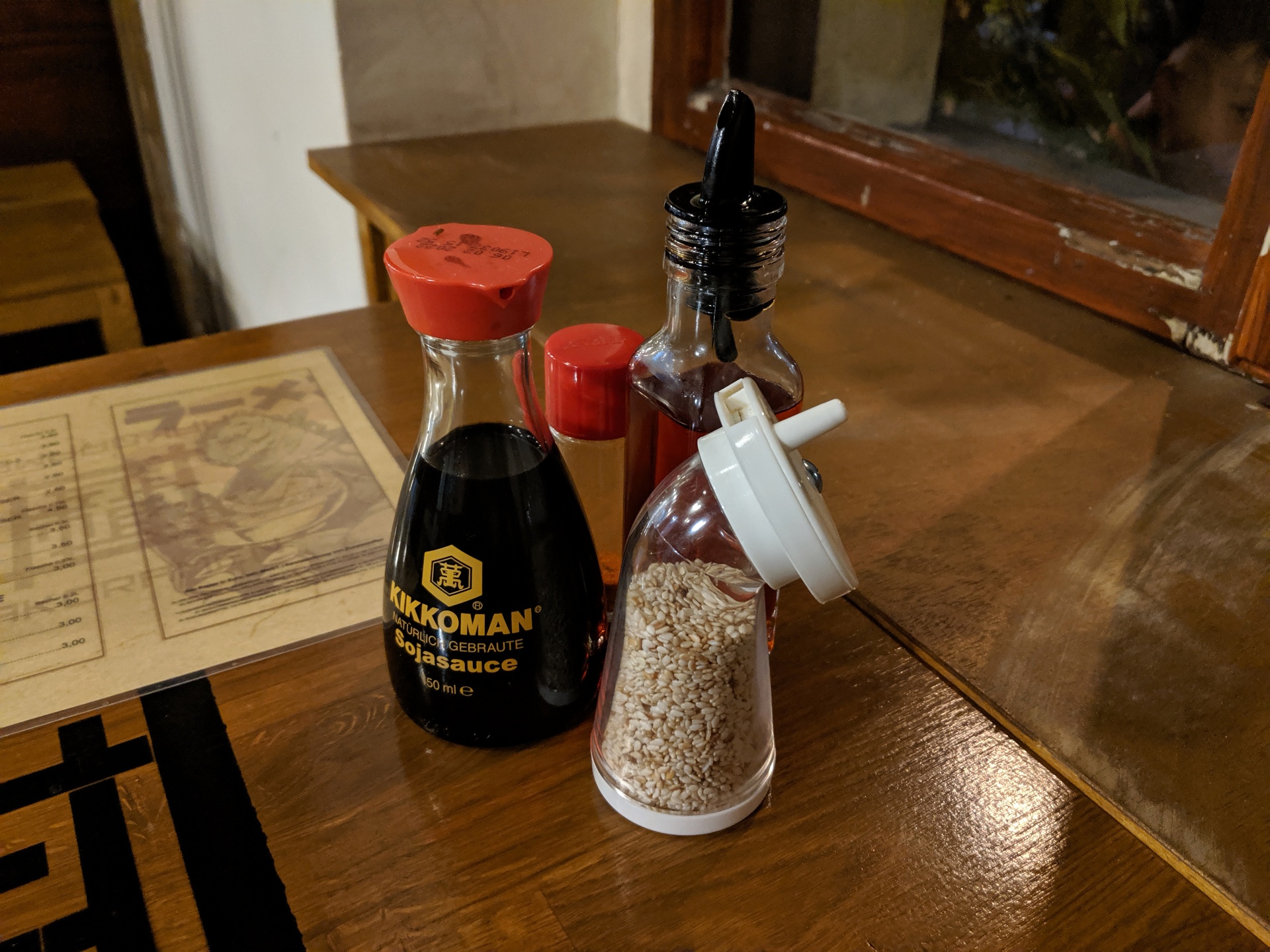 Soy sauce, sesame seeds in a grinder, chili oil, and chili powder