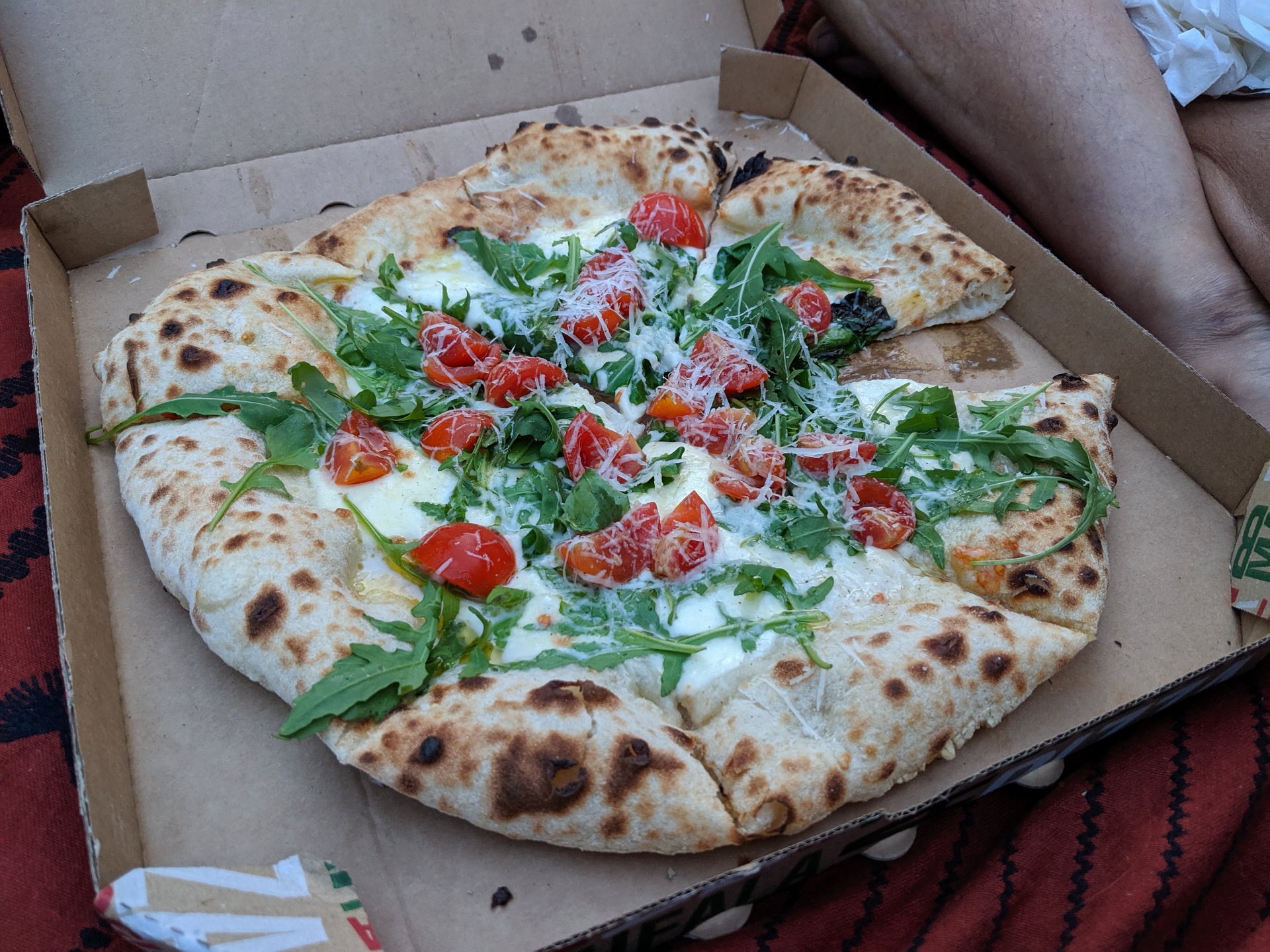 The pizza with buffalo mozzarella, rucola, and tomatoes