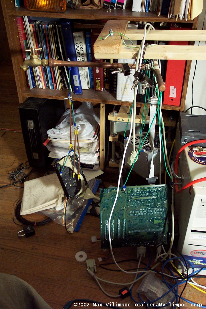 A close up view of the hanging computer parts. In the background, a shelf full of books, and the Hellbender Archive computer