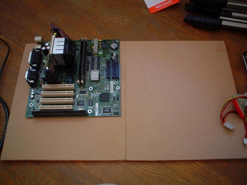 A microATX motherboard placed atop a piece of middle-density fiberboard panel